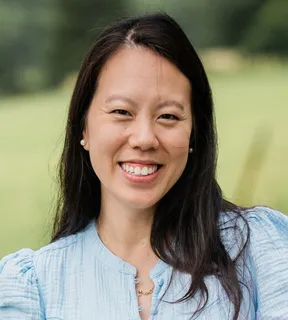 Dr. Nancy Ha, smiling, outdoors on a summer afternoon.